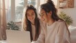 © Studium L&M - Two young girls smiling and looking at a laptop in a sunny, cozy room.