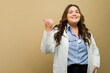 Cheerful plus-size female doctor, pointing towards copy space,  exuding confidence and positivity in a studio setting