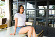 Beautiful latin woman in a simple white t-shirt smiling for mockup shots in a relaxed outdoor cafe setting
