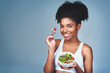 © peopleimages.com - Space, portrait or black woman with salad in studio for healthy meal, nutrition diet or digestion benefits. Mockup, vegetables and happy female fitness model eating food isolated on blue background