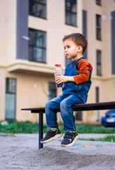 Sticker - A young boy sits on a bench with a bottle of water in his hand. The scene is set in a park, with a car parked nearby.