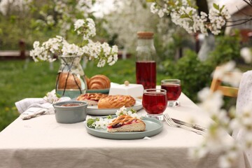 Canvas Print - Stylish table setting with beautiful spring flowers, fruit drink and pie in garden