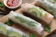 Delicious spring rolls and sauce on wooden table, closeup