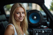 A beautiful blonde girl at an auto sound competition. Car music. Subwoofers, amplifiers, acoustics. Car audio system.