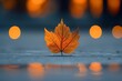 A single autumn leaf on a wet sidewalk with blurry orange streetlights in the background.