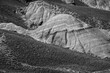 Striking black and white photo capturing the detailed textures and dramatic contours of barren hills. The image evokes a sense of solitude and rugged beauty.