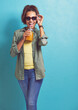 Excited woman, portrait and sunglasses with orange juice in fashion for vitamin C on a blue studio background. Female person, brunette or model with smile for citrus drink or fresh beverage on mockup