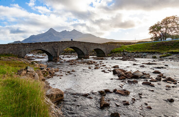 Wall Mural - Sligachan Bridge, Isle of Skye, Scotland, with Cuillin Mountains and orange clouds on backround in sunset light, Isle of Skye, Scotland