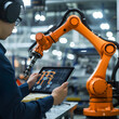 An engineer uses a digital tablet to control a robot arm in an auto parts factory. which is a high-tech industry.