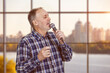 Portrait of mature man singing or giving a speech in microphone. Indoors checkered windows background.