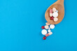 many colorful drug medicines or pill in a spoon on blue table background, healthy and medicine concept
