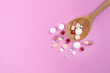 many colorful drug medicines or pill in a spoon on pink table background, healthy and medicine concept
