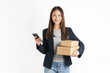 Smiling beautiful Asian woman holding cardboard boxes and hands using smartphone on white background. Concept delivery online.