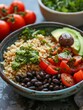 A high-angle view of a simple grain bowl with brown rice, black beans, and avocado.