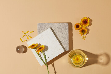 Wall Mural - A stack of two stone podiums displayed with Calendula flowers, a glass ball and a conical flask filled with liquid of Calendula flower extract. Minimal podium display for cosmetic product presentation