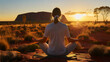 © jixiang - A woman with tied-up hair meditating at Uluru, Australia during sunset
