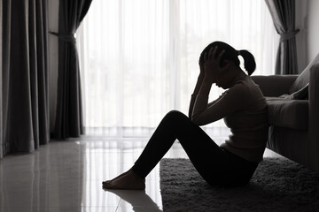 Depressed woman, Silhouette of teenager girl with depression sitting alone  in the dark room. Black and white photo.