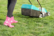 Woman mowing the lawn with a grass trimmer machine