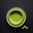 Top view of finely ground matcha tea powder in a cup and scattered around the cup on the surface against a black background close up.