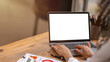 © Wasana - Close-up of a professional's hands typing on a laptop with a white screen, perfect for mockup designs, on a wooden desk.