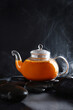 Hot tea with sea buckthorn in a transparent glass teapot. A healthy drink. Natural vitamin C. Photo on a black background.