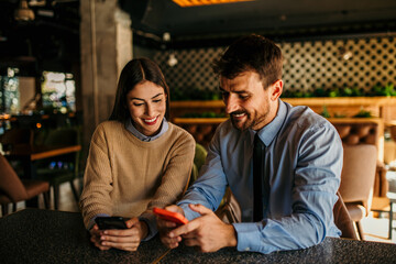 Wall Mural - Man, woman have a teamwork on a smartphone, remote working at coffee shop