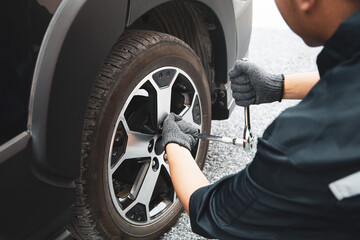 Auto mechanic use wrench to repairing and change car tires. Concept of car care service and maintenance or fix the car leaky or flat tire.