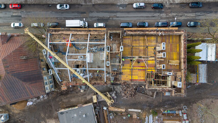 Drone photography of construction workers building new rooftop on old building during spring day