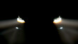 Turned on headlights of a modern, sports car on a black background. Concept of automobile services, advertising of modern cars.
