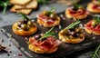 © volga - Gourmet appetizers with prosciutto, olives, and herbs on slate