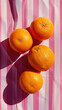 3 oranges on a pink striped uniform background