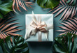 Creative floral concept. A white gift box with gold ribbon bow surrounded with tropical green Monstera leaves and palm Split Leaf. Mock up product presentation. top view, flat lay	
