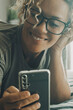 Cheerful modern young woman smile and use mobile phone to chat or call. Technology online smartphone app and people. Female wth glasses reading on cell. Connection and communication device cellphone