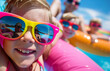 Children with inflatable toys in the pool, closeups of their faces, wearing colorful sunglasses and smiling happily