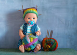 Fototapeta Natura - A doll with an unfinished knitted hat and a skein of yarn with knitting needles.