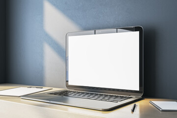 Wall Mural - close up of empty white computer screen on simple wooden desk. blue wall background. workplace conce