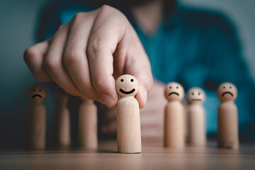 Poster - Businessman pushing smile wooden figure in front of sad figure for positive mindset and excellent quality customer evaluation survey after use product and service concept.