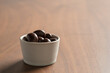 Chocolate covered cashew nuts in a bowl on wood table