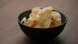 potato chips in black bowl on wood table