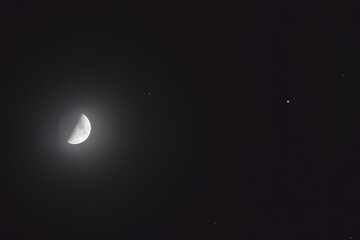 Wall Mural - The mineral Moon in its first quarter phase, in conjunction with the star Pollux in the Gemini constellation and some background stars. You can see the earth-shine in the shadowed part.