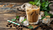 Coffee iced cocktail drink with frozen ice cubes, milk and mint leaves. Wooden background