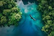 An aerial view of a long boat on a blue river in a green jungle with white sandbars.