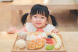 Asian kid girl  eating a plate of desserts with smiling face. Happy childhood.