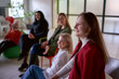 © Victoria Antre - a woman makes a speech on stage, colleagues laugh at her jokes sitting on chairs and ottomans in the hall, office location