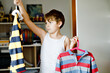 © Irina Schmidt - School kid boy standing by wardrobe with clothes. Child making decision for school shirt to wear. Children get dressed in the morning for school.