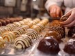 A person is making chocolate covered desserts. The desserts are in various shapes and sizes, and some have chocolate drizzled on top. Concept of creativity and indulgence