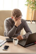 © Ann Stryzhekin - tired upset young man working on laptop at table.
