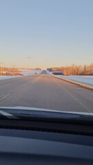 Wall Mural - Car driving on highway with snow on roadsides during wintertime in the evening