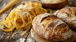 Hearty loaves of crusty bread beside golden ribbons of pasta on a timber surface hinting at a baker's table