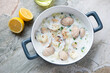 New England chowder with vongole clams in a serving pan, horizontal shot on a light-grey granite background, high angle view
